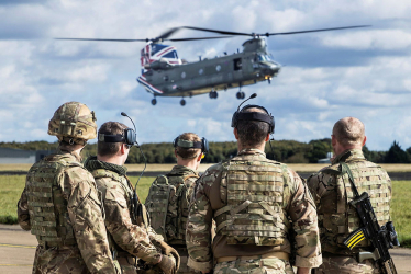 Picture of a group of soldiers watching an Apache Helicopter.